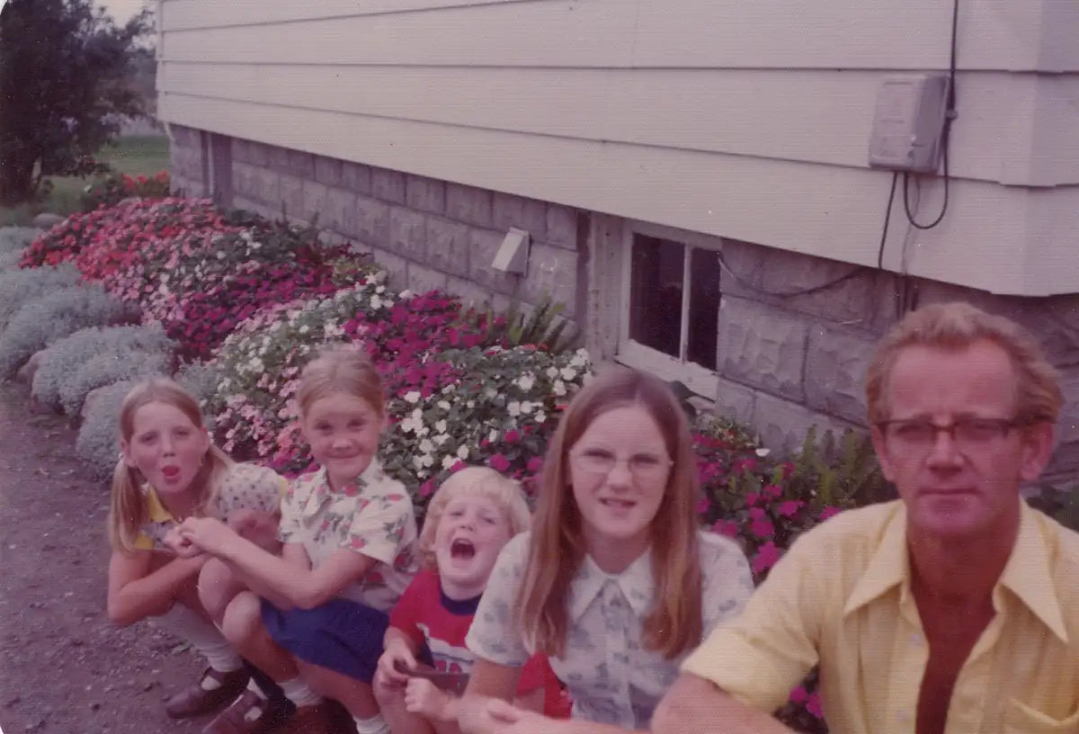 Adrian Vandermeer and four children making silly faces, sitting in front of home and garden in 1971.