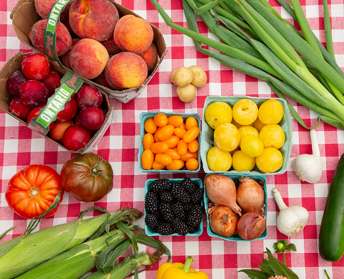 Flatlay of Ontario-grown fruits and vegetables on a red and white checkered tablecloth.