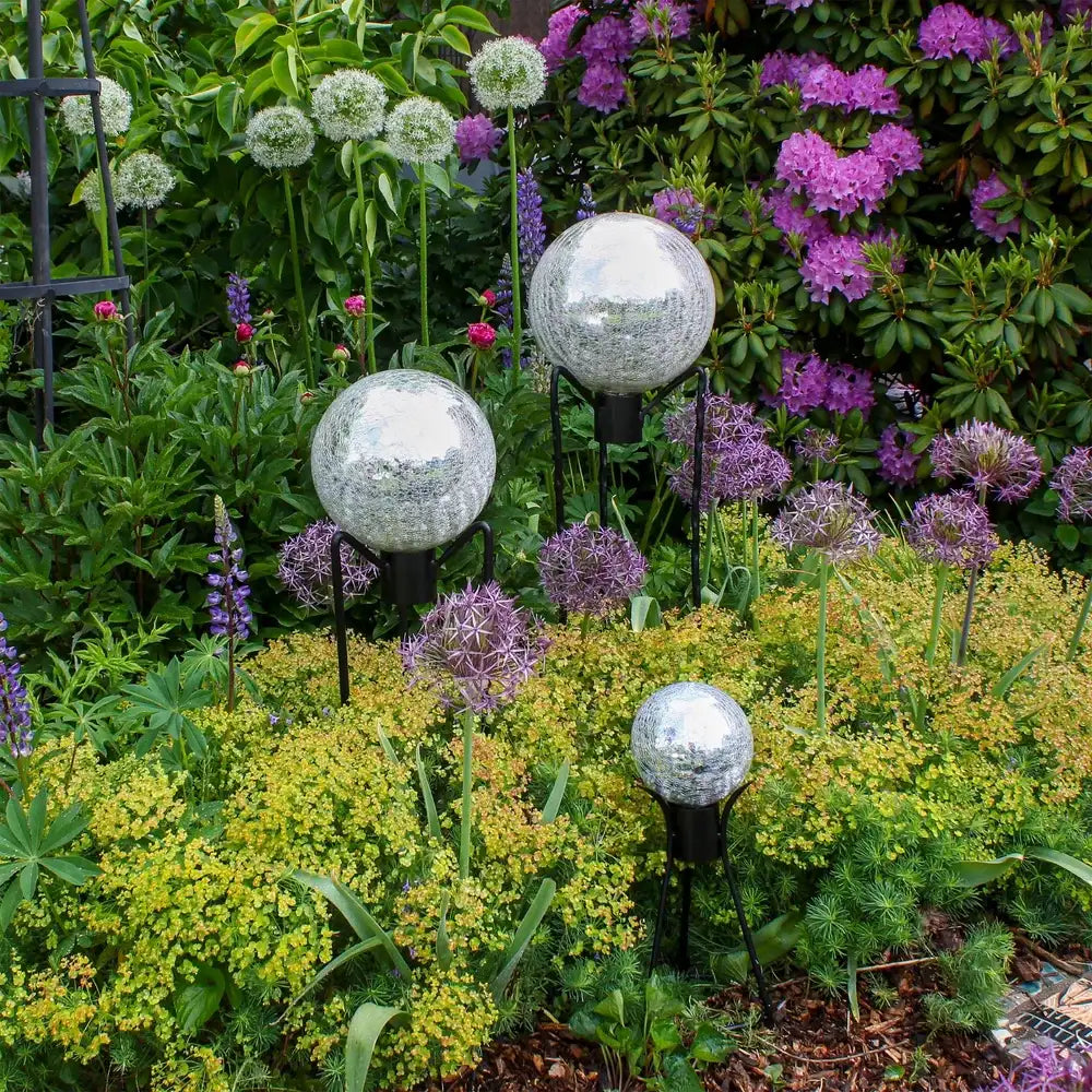 Decorative gazing balls in a garden setting with flowers and plants.