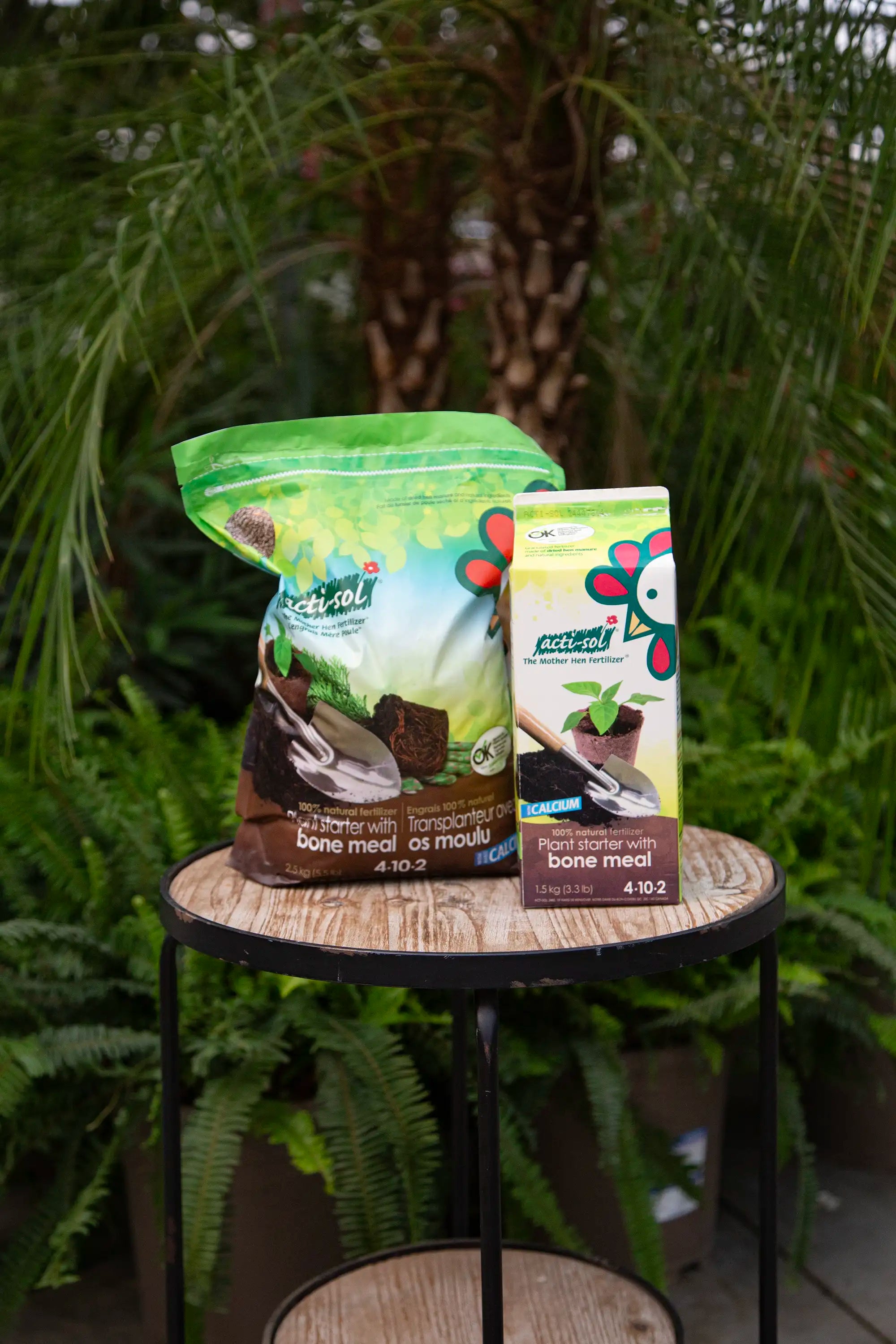 Two bags of Actisol fertilizer on a table with plants in the background