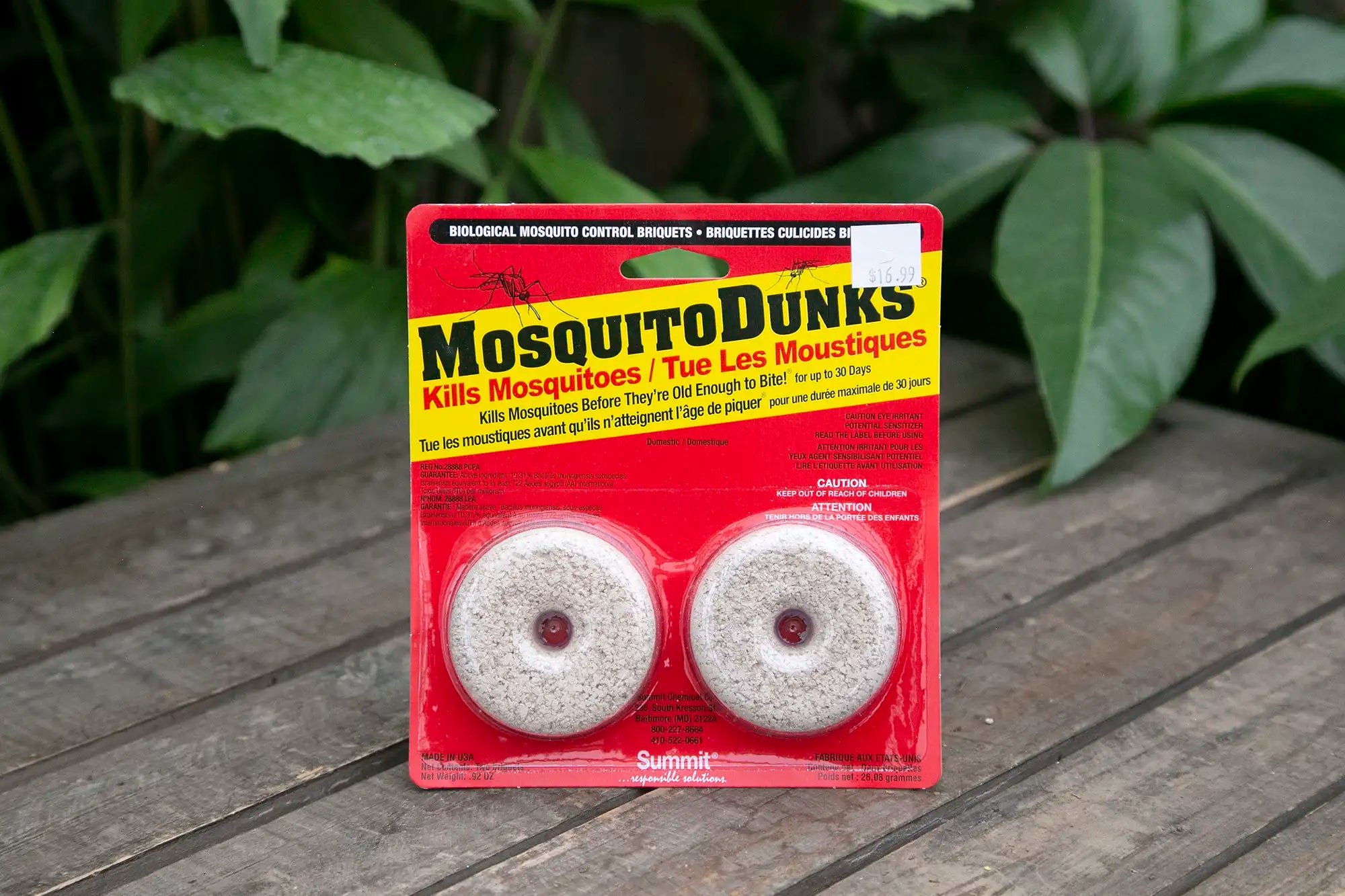 Mosquito Dunks on a wooden surface with green leaves in the background