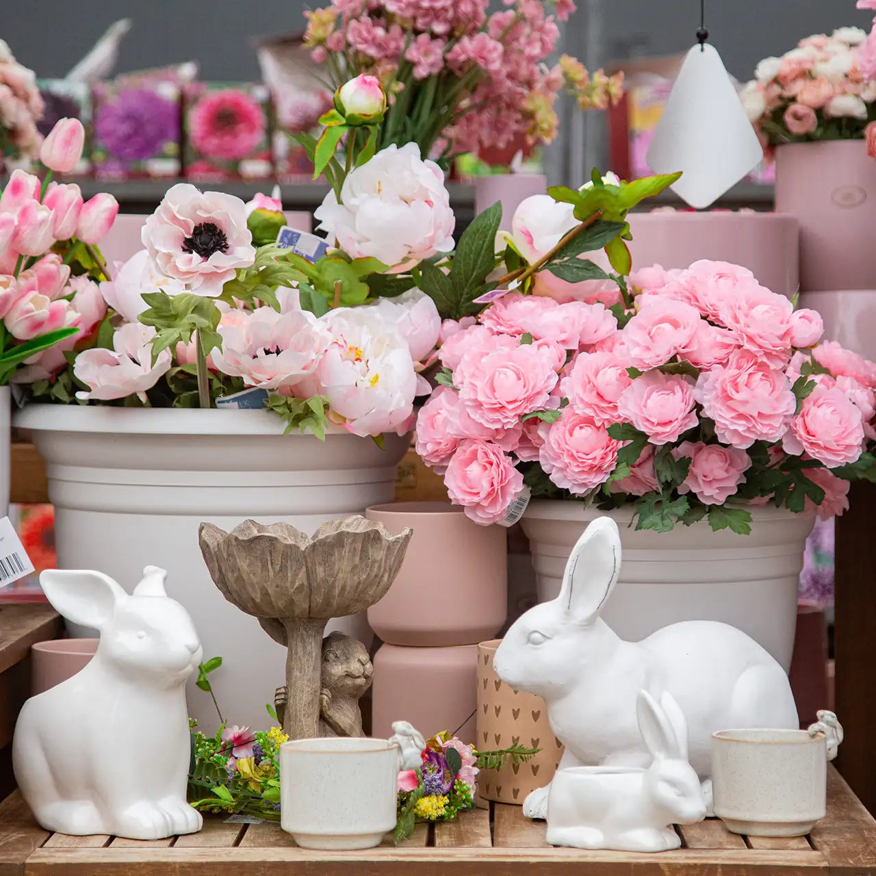 Display of faux spring flowers in pink shades with easter decor in greenhouse