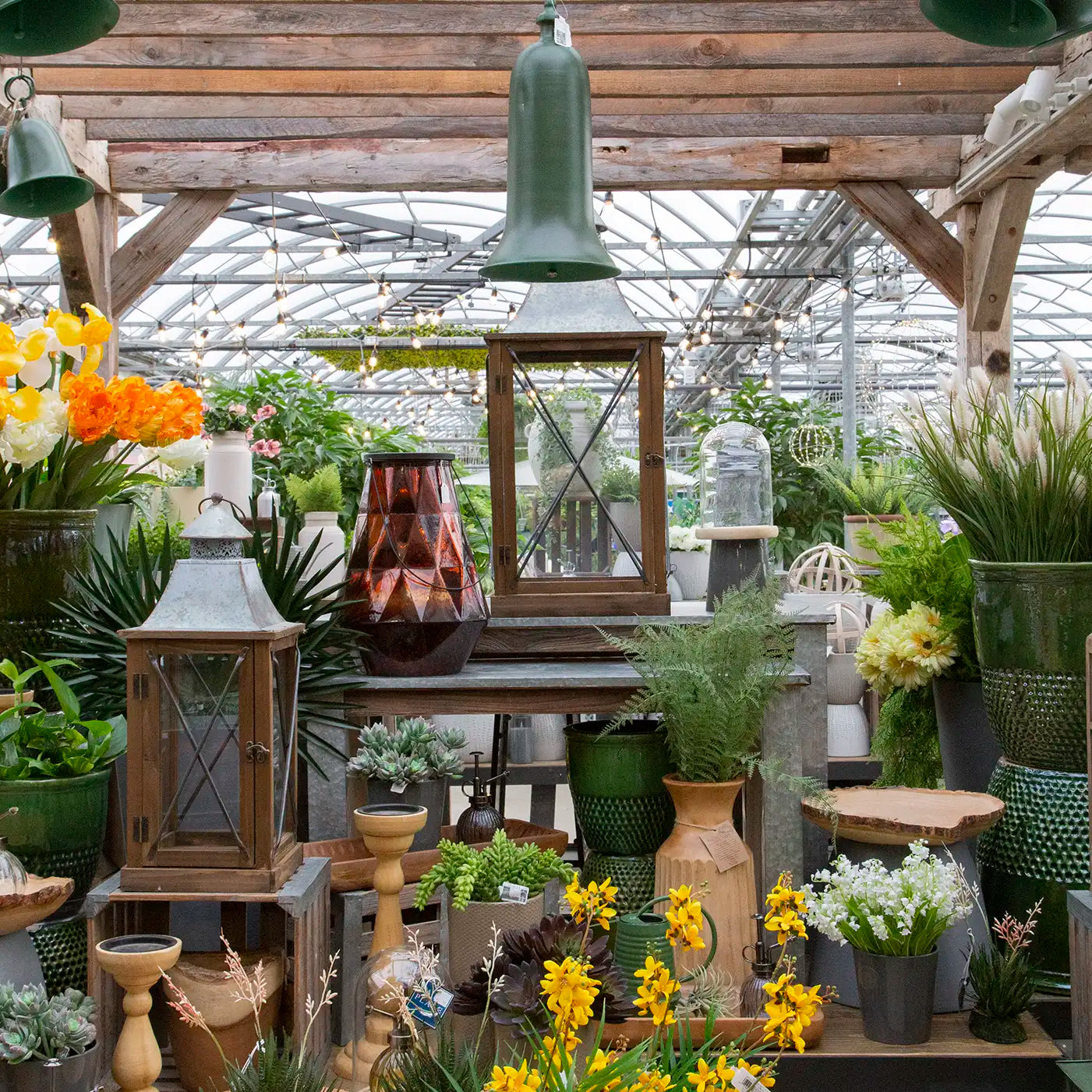 Indoor garden center display with artificial flowers, lanterns, home decor, and hanging bells.