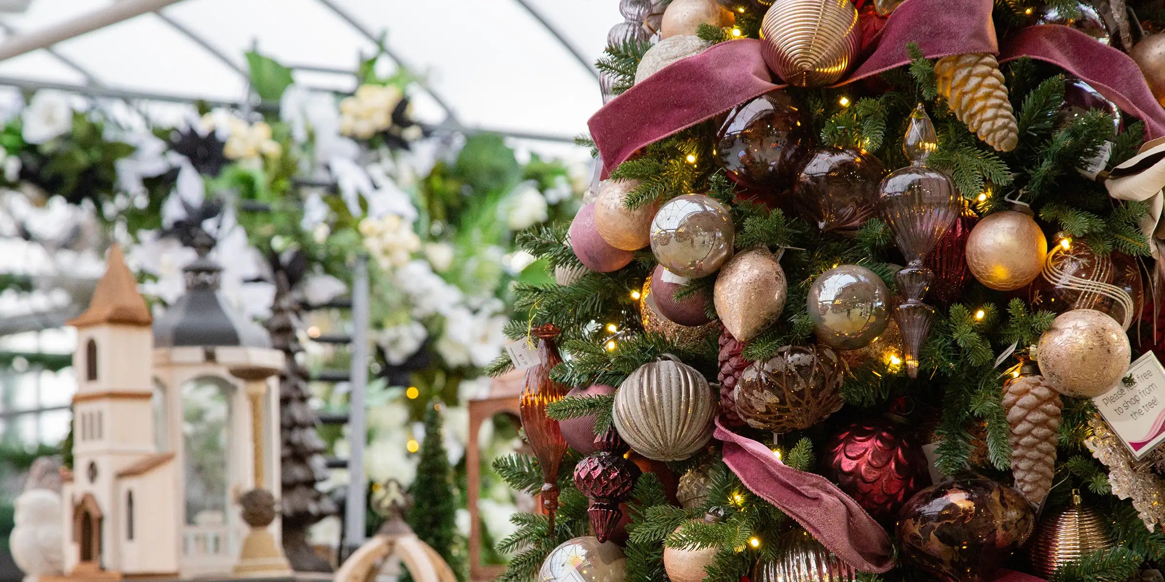 Decorated Christmas tree with ornaments and lights in a greenhouse setting