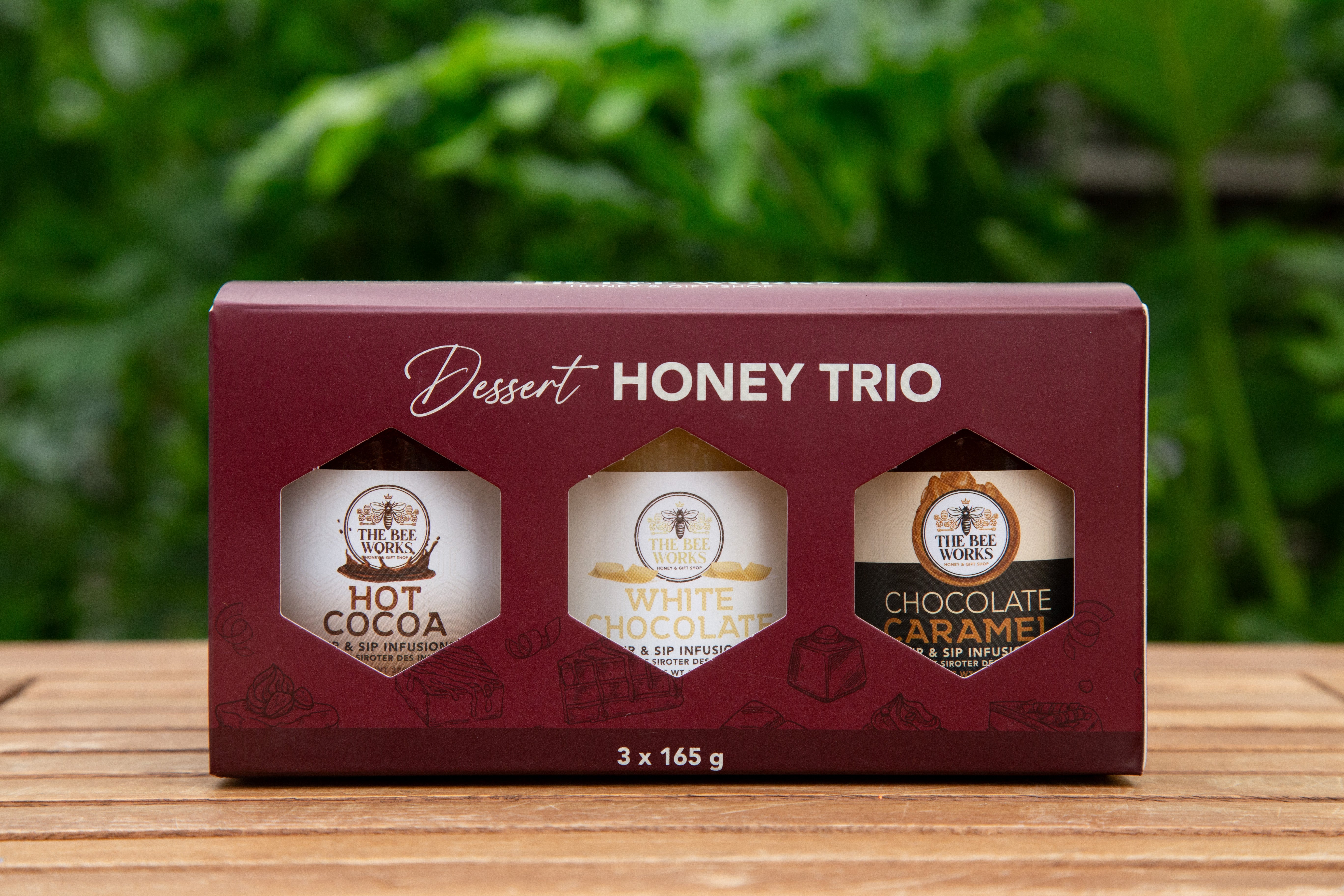 Box with three different types of honey on a wooden surface.