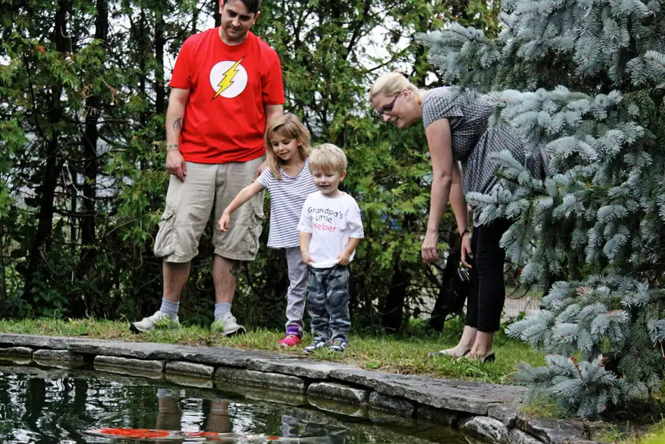 Family by a pond of koi with trees in the background