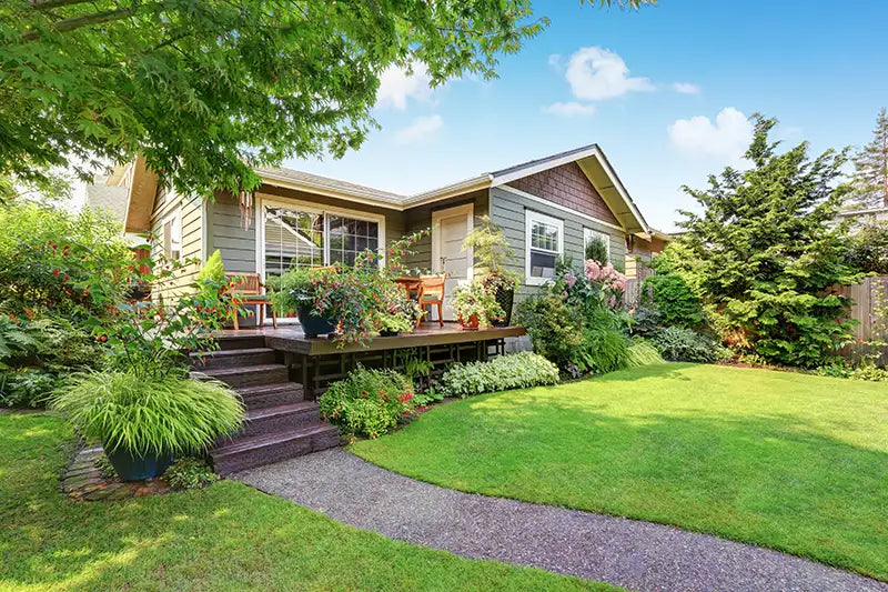 House with a garden exposed to some sun with tree shading part of it.